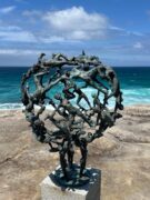 A sculpture depicting figures on a rock, set against the backdrop of a serene ocean landscape.